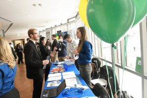 A student in professional attire speaks with a potential employer across a table at Career Fair. 