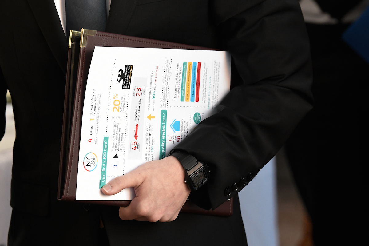 A person holds a portfolio and paper with colorful writing on it related to business.