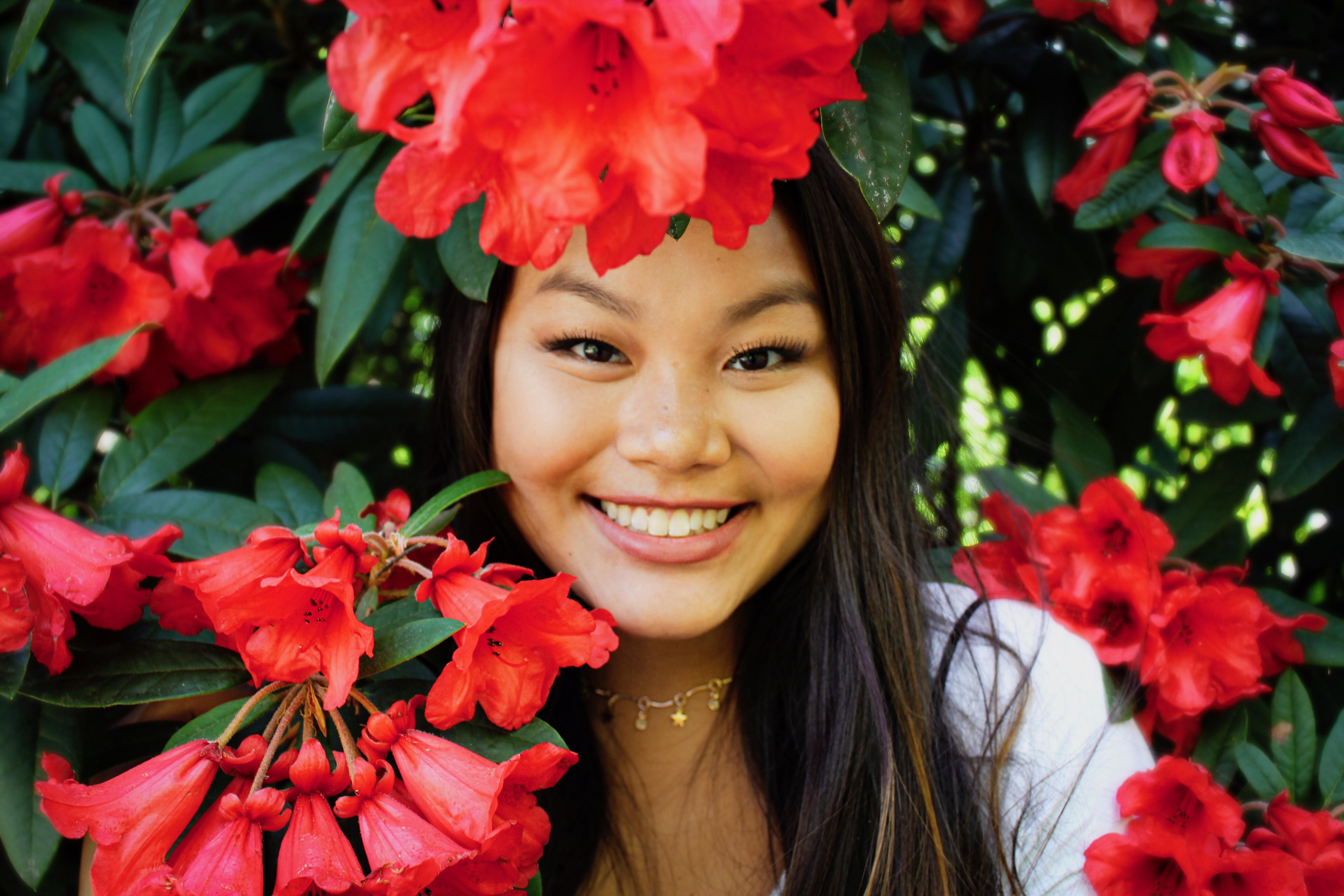 Clarkson student Jada Flanagan looks at the camera surrounded by beautiful red flowers.