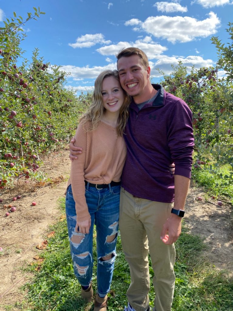 A couple standing in an apple orchard 