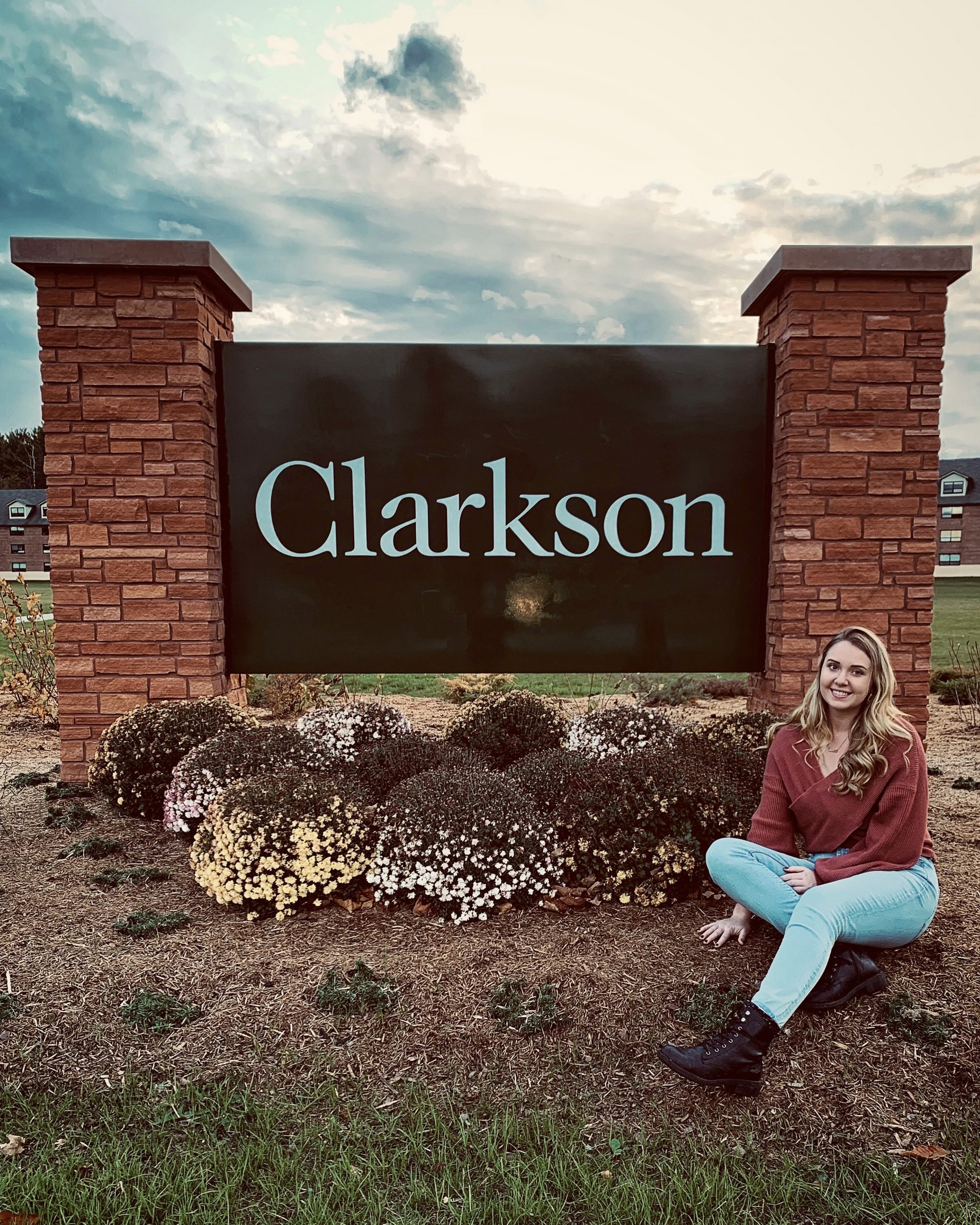 Megan Walseman sitting next to the Clarkson University sign