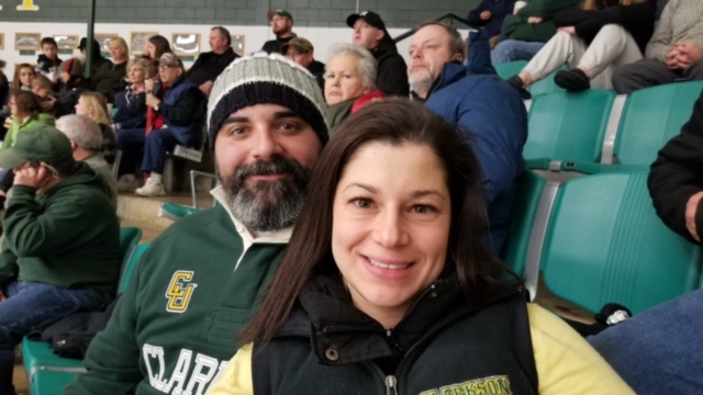A couple pose for a selfie in the crowd at a hockey game.