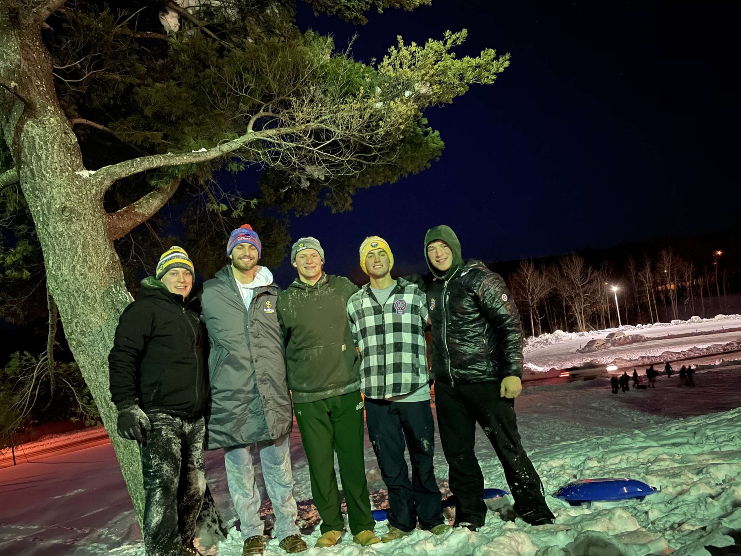 Five students pose outside at night.
