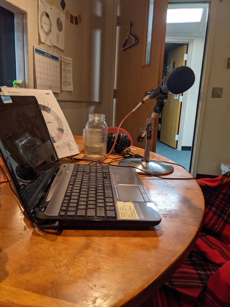 A table that has a laptop on it with a microphone stand