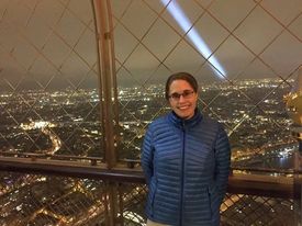 Katie on the top of the Eiffel Tower, Paris cityscapes can be seen in the background