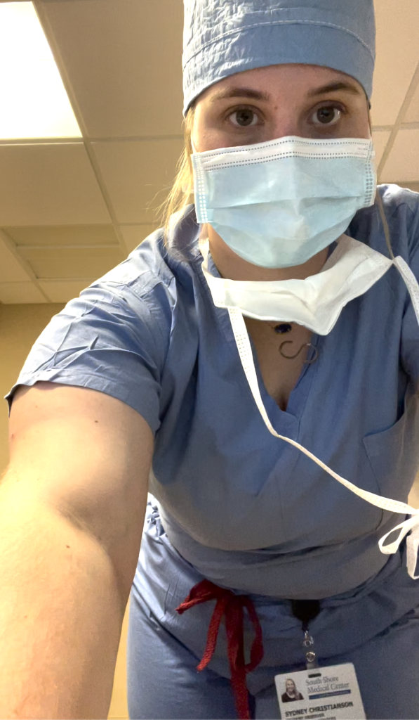 A person in full scrubs leaning down to take a selfie