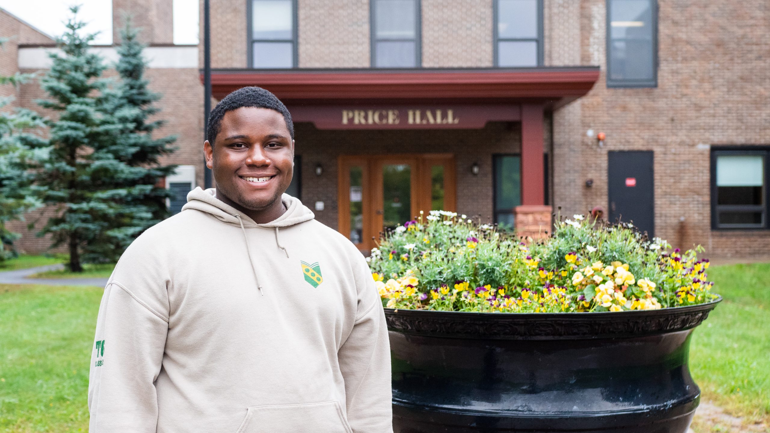 Devaun Baker, a Clarkson University student posing in front of the Price Hall building.