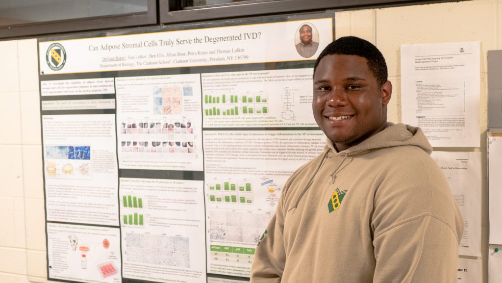 DeVaun standing in front of his research poster.