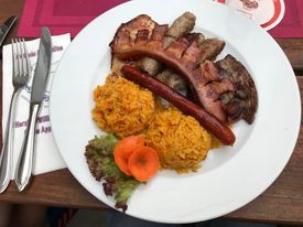 A white plate that has meat and rice, and vegetables on it 
