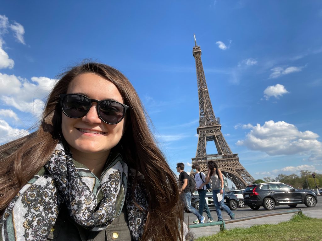Person standing next to the Eiffel tower