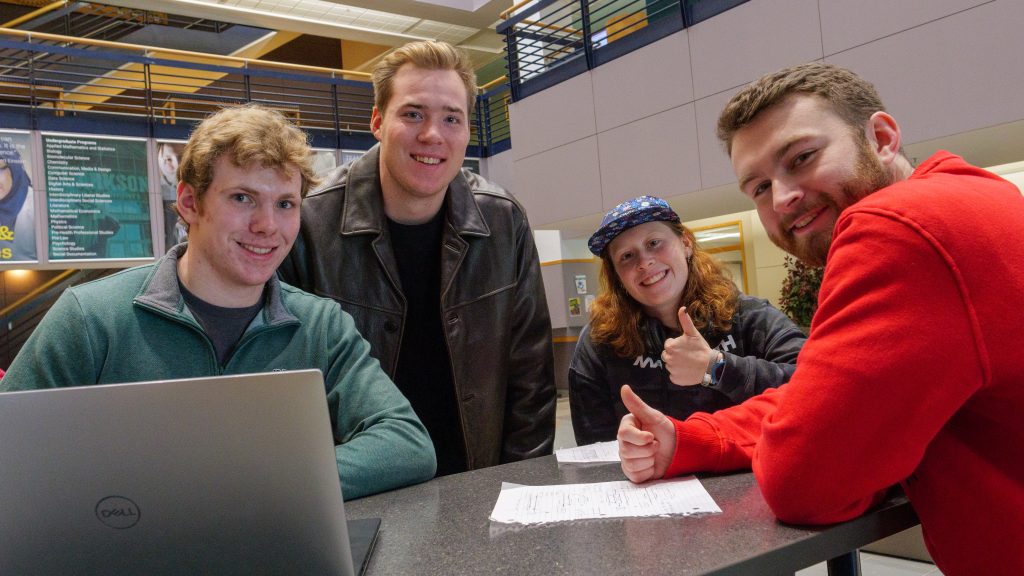 Four Senior Design classmates working together on a student engineering project to make sidewalks more efficient.